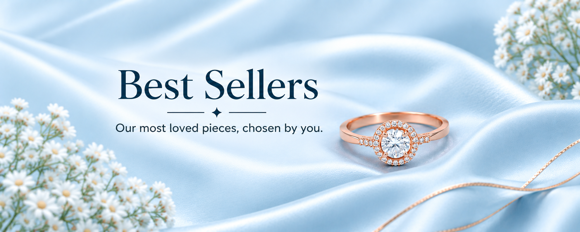 A rose gold engagement ring with a round-cut center stone and small surrounding accent stones, displayed on light blue satin fabric with white flowers and the text 'Best Sellers' on a banner.