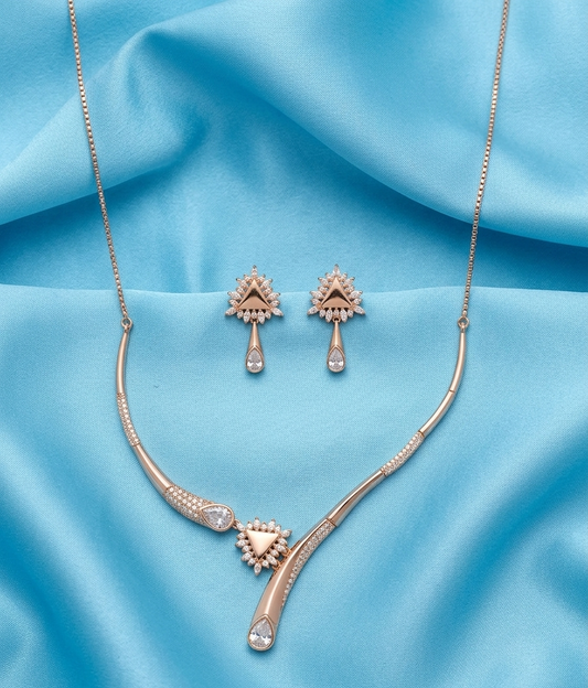 A rose gold jewelry set featuring a curved necklace and matching drop earrings, displayed on a draped light blue satin fabric background.