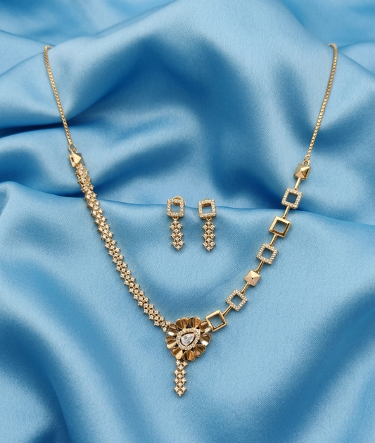 Gold jewelry set featuring a necklace and matching earrings, displayed on a draped light blue satin fabric background.